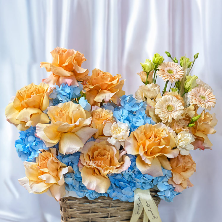 Персиковые розы с синими гортензиями в корзине (крупный план)